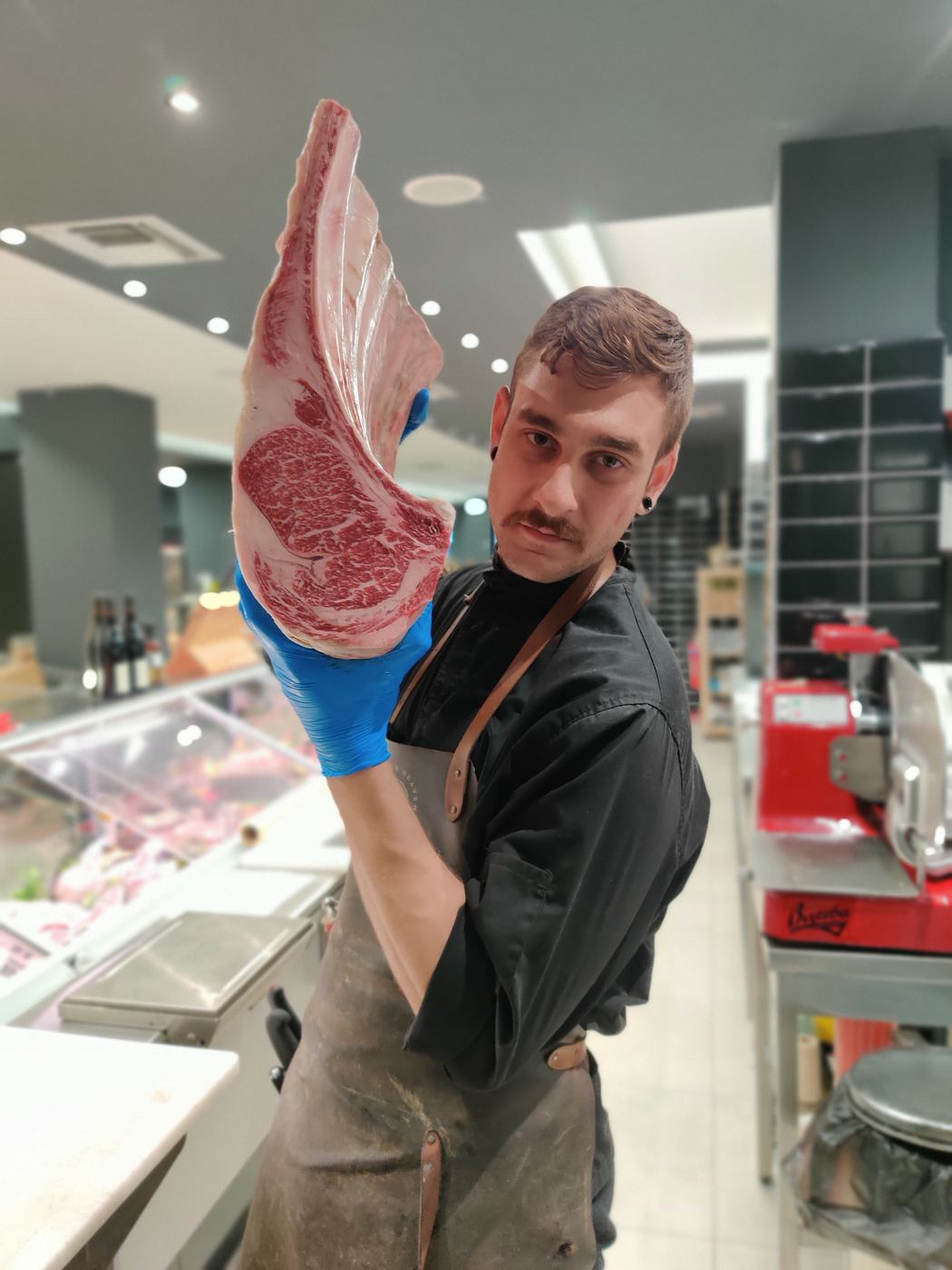 Christos holding up a large marbled ribeye cut